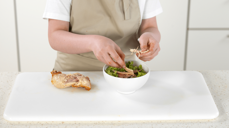Bruk fingrene og riv kyllingkjøttet i biter. Legg det i salatskålen. Kast skinn og ben i søpla.