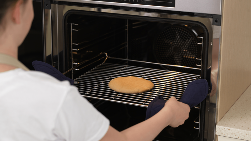 Finn frem et kaldt stekebrett. Bruk grytekluter, ta risten forsiktig ut av ovnen og sett den på stekebrettet.