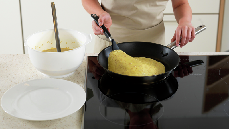 Når pannekakerøren begynner å stivne kan du sjekke om pannekaken har fått en fin gyllen brunfarge på undersiden. Bruk en stekespade.
