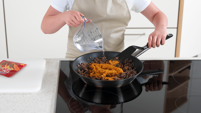 Ha tacokrydder og vann i stekepannen, bland godt og stek videre i 2 minutter. Skru av platen og skyv stekepannen til side.