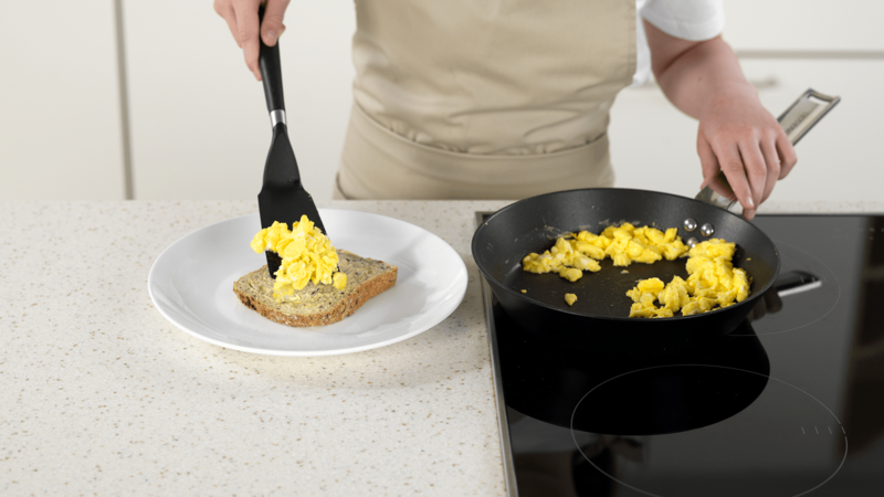Når eggerøren er helt stiv, skyv stekepannen vekk fra platen. Bruk stekespaden til å løfte eggerøre over på en tallerken med en ferdigsmurt brødskive. Legg cherrytomat på toppen.