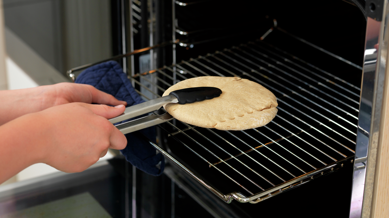 Bruk en klype og ta pitabrødet ut av ovnen. Legg det på skjærefjølen.