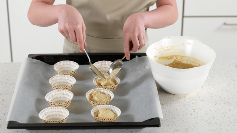 Bruk 2 spiseskjeer til å fylle i muffinsformene. La det være igjen litt plass, slik at muffinsene kan heve mens de steker.