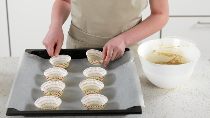 Sett muffinsformer på et stekebrett med bakepapir, med fire i hver rad. Du kan også sette muffinsformene i et muffinsbrett.