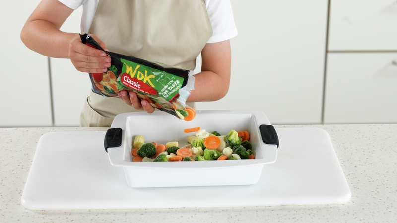 Finn frem en ildfast form. Klipp opp posen med wokgrønnsaker og ha dem i den ildfaste formen.
