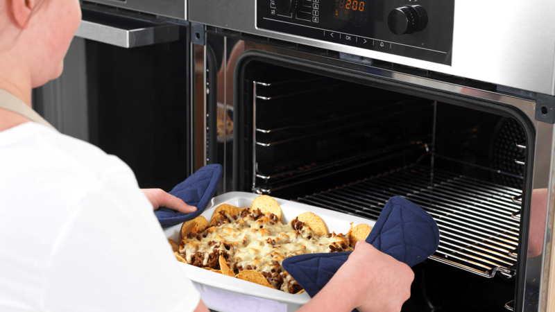 Bruk grytekluter og ta nachosen ut av ovnen. Sett den varme formen på gryteunderlaget du har gjort klart.