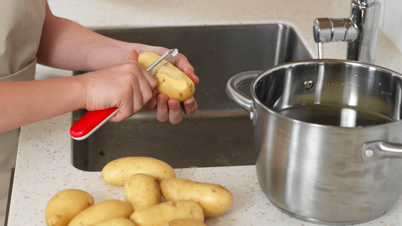 Skyll og skrell potetene over vasken og legg dem i kjelen med vann. Husk å kaste skallet i spøla når du er ferdig.