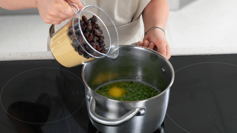 Trekk kjelen fra platen når vannet koker, hell i couscous og rosiner.